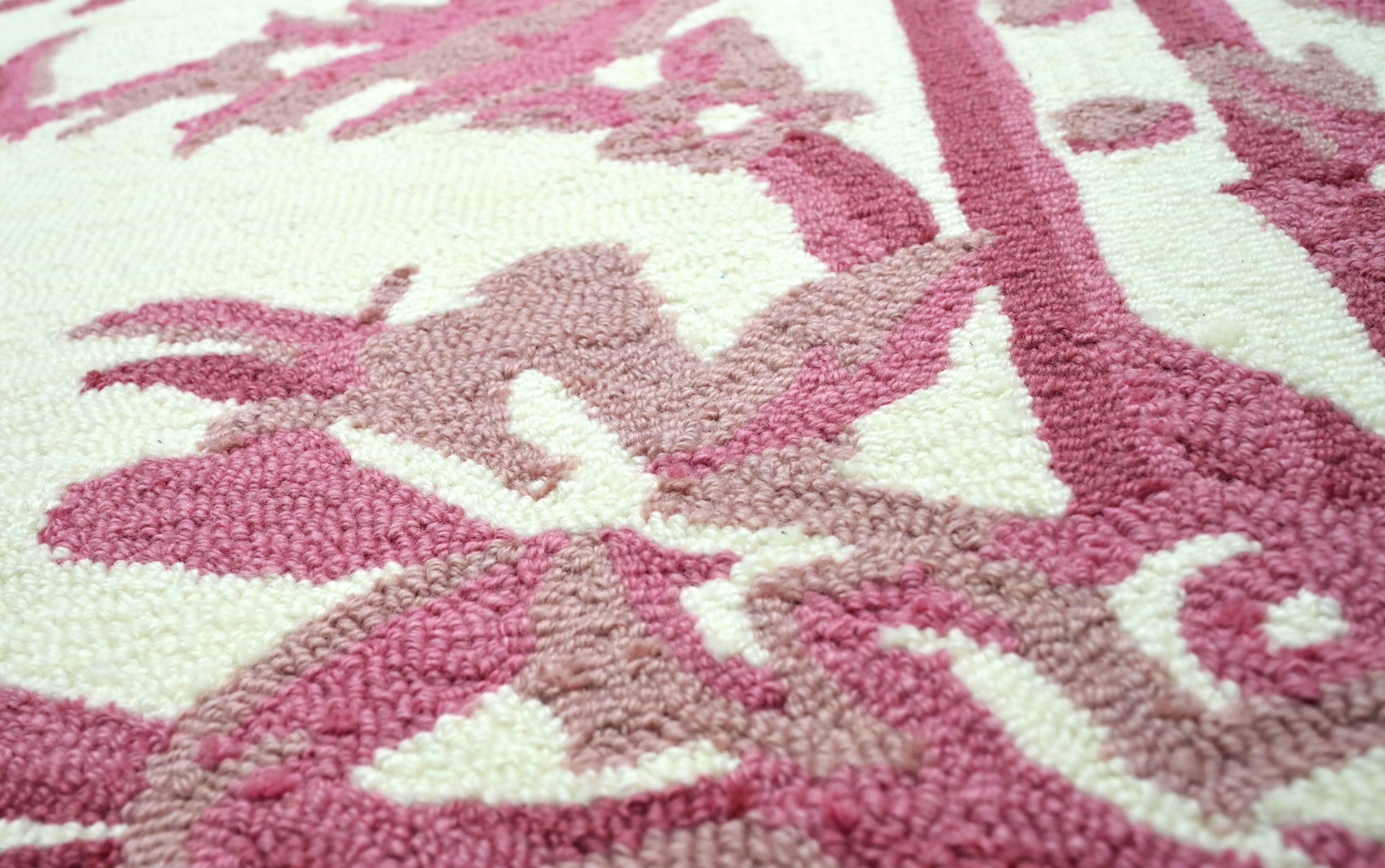 Close up of blush pink hand tufted loop rug highlighting detailed floral border pattern