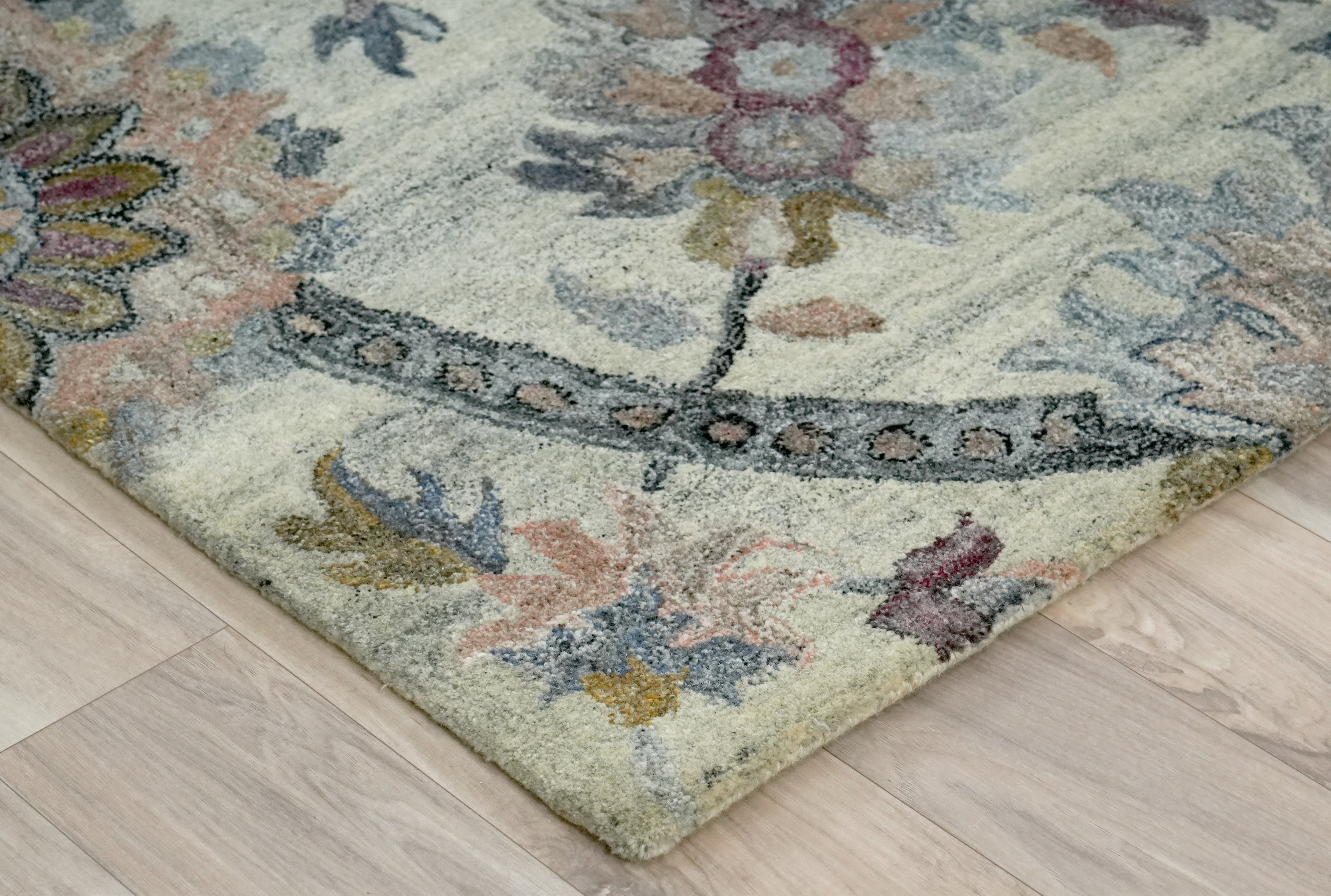 Folded corner detail of Briarwood hand tufted rug showing dense pile and intricate floral weaving.