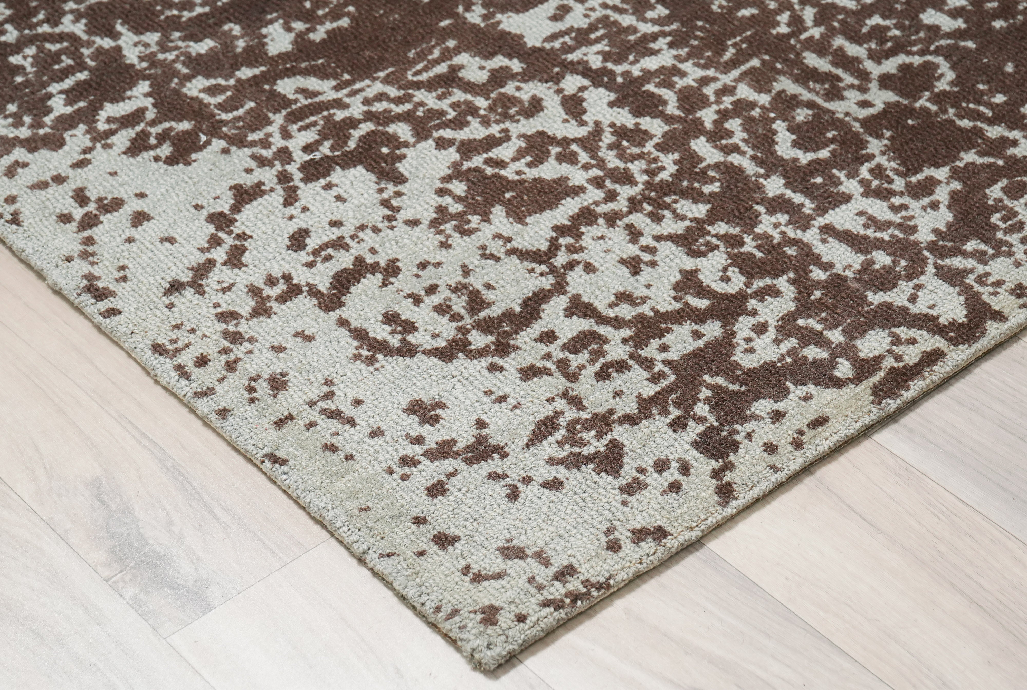 Cocoa Relic wool rug corner detail showing ivory base and deep brown distressed pattern.