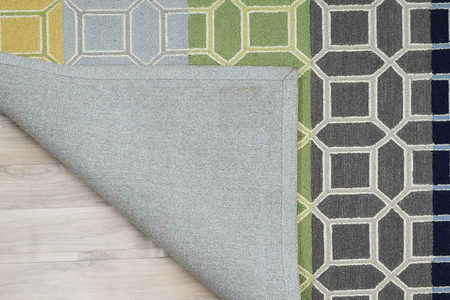 Colorband Wool Rug made from 100 % New Zealand wool with hand tufted construction showing a folded corner revealing the backing and geometric lattice pattern with multicolor bands