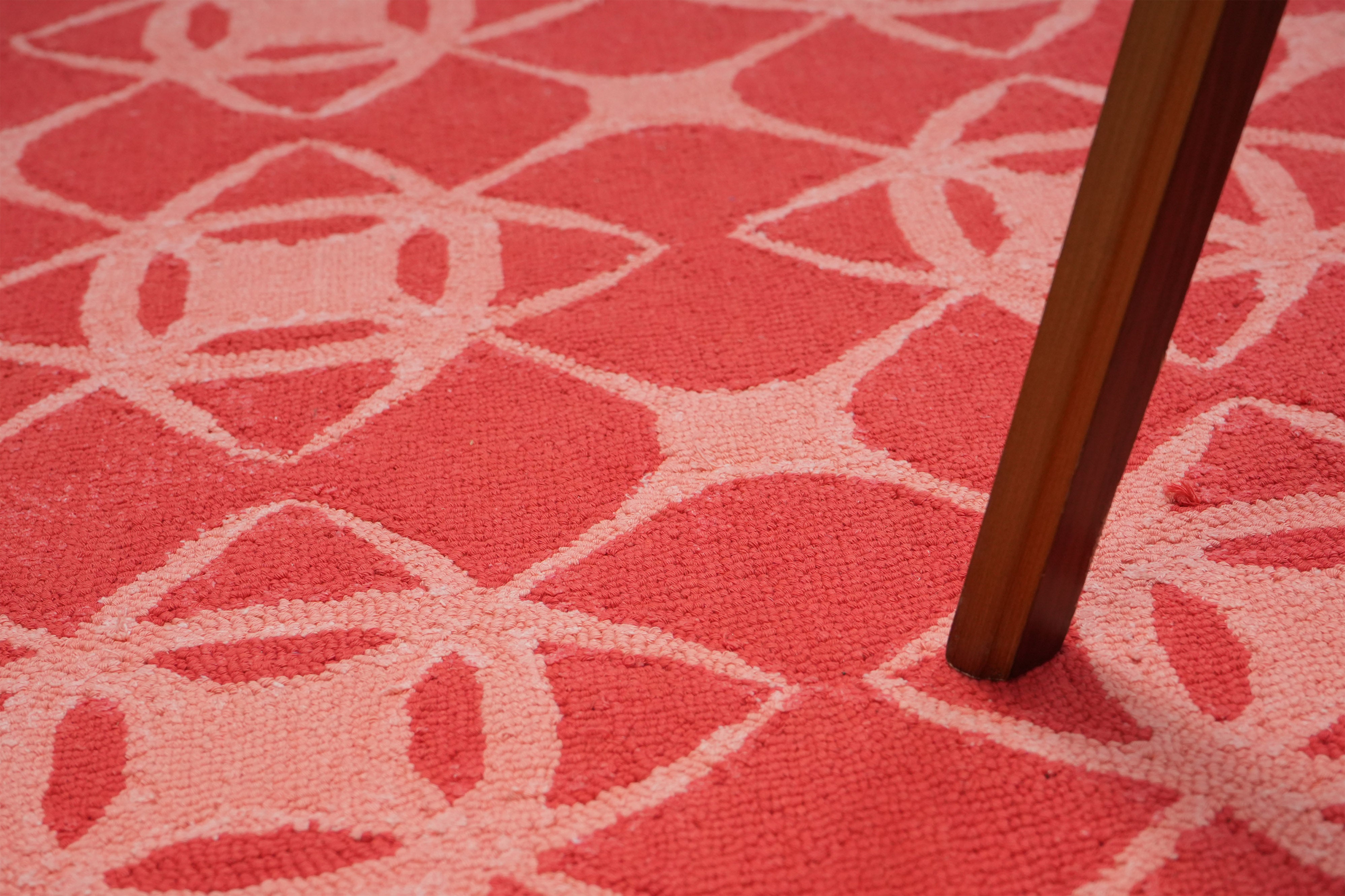 Coral Cipher hand tufted wool rug detail under table leg showing geometric pattern in coral and blush tones