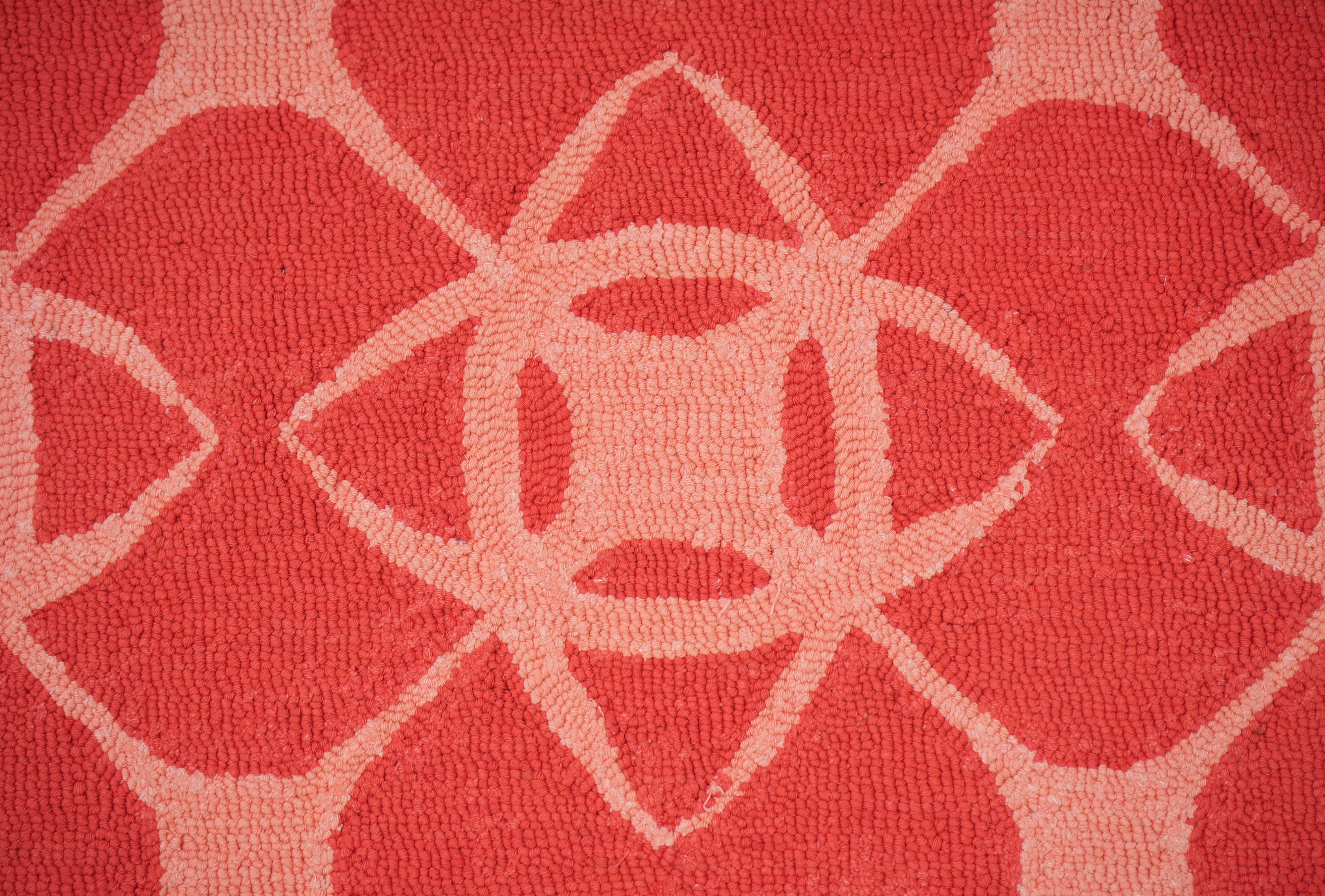 Close up of Coral Cipher hand tufted wool rug showing geometric interlocking pattern in coral and blush
