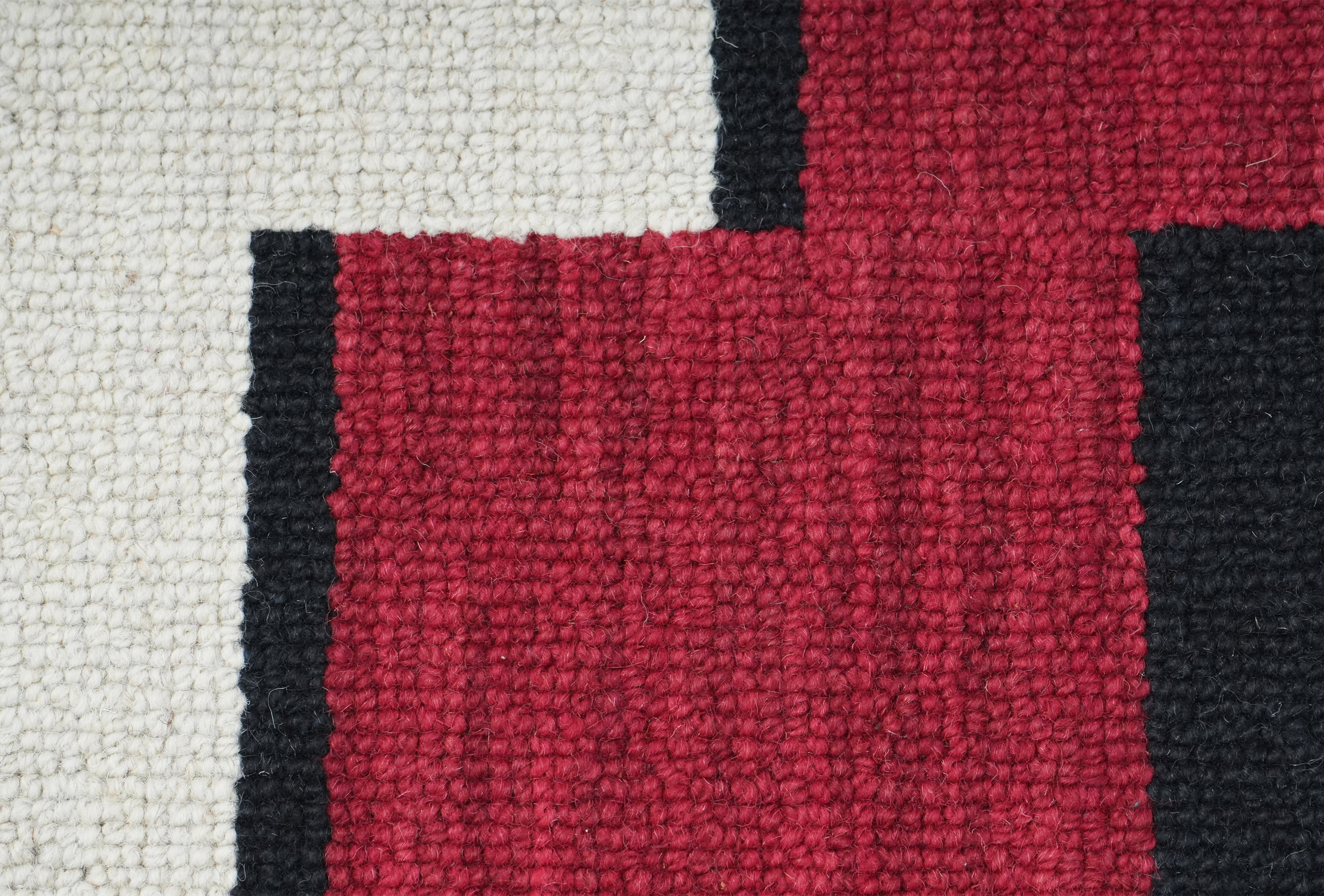 Close up texture of Corvane hand tufted rug in crimson and ivory tones.