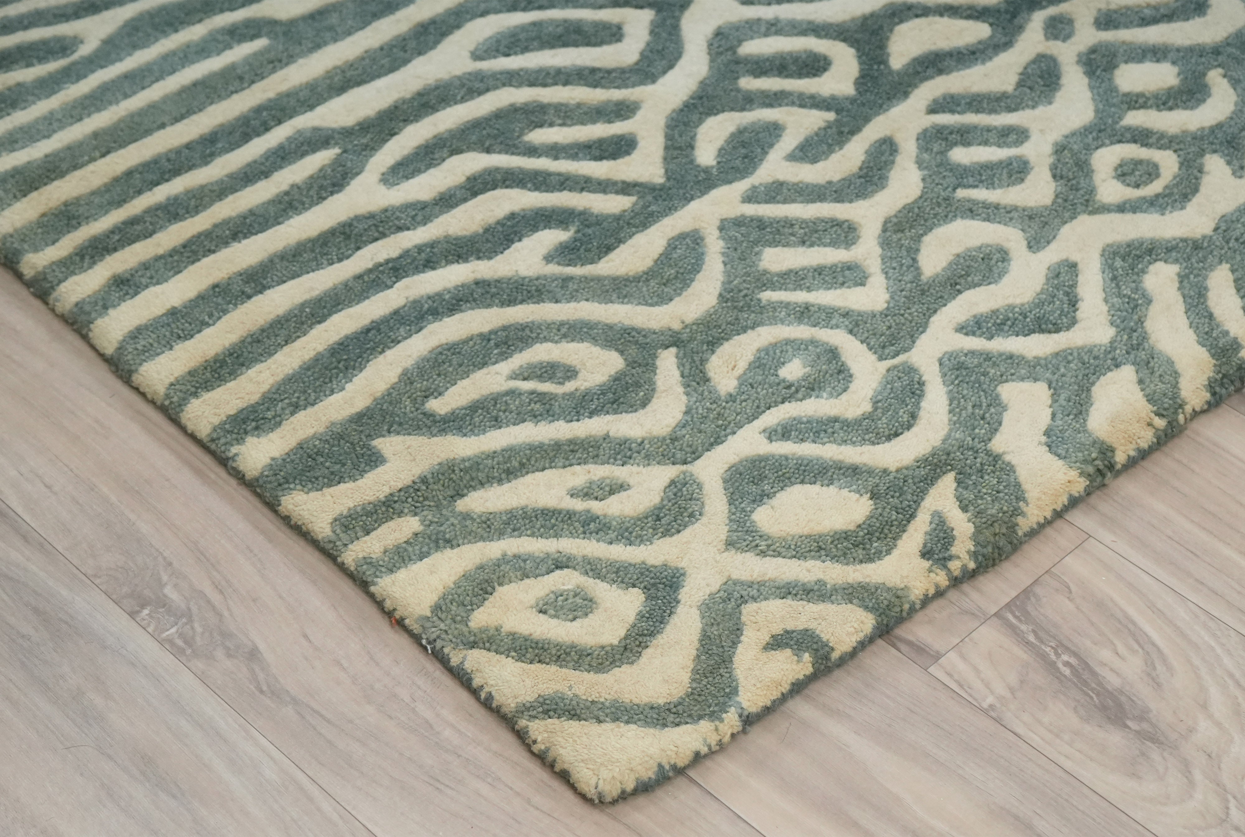 Glyph hand tufted wool rug corner detail showing maze pattern in sage green and ivory tones