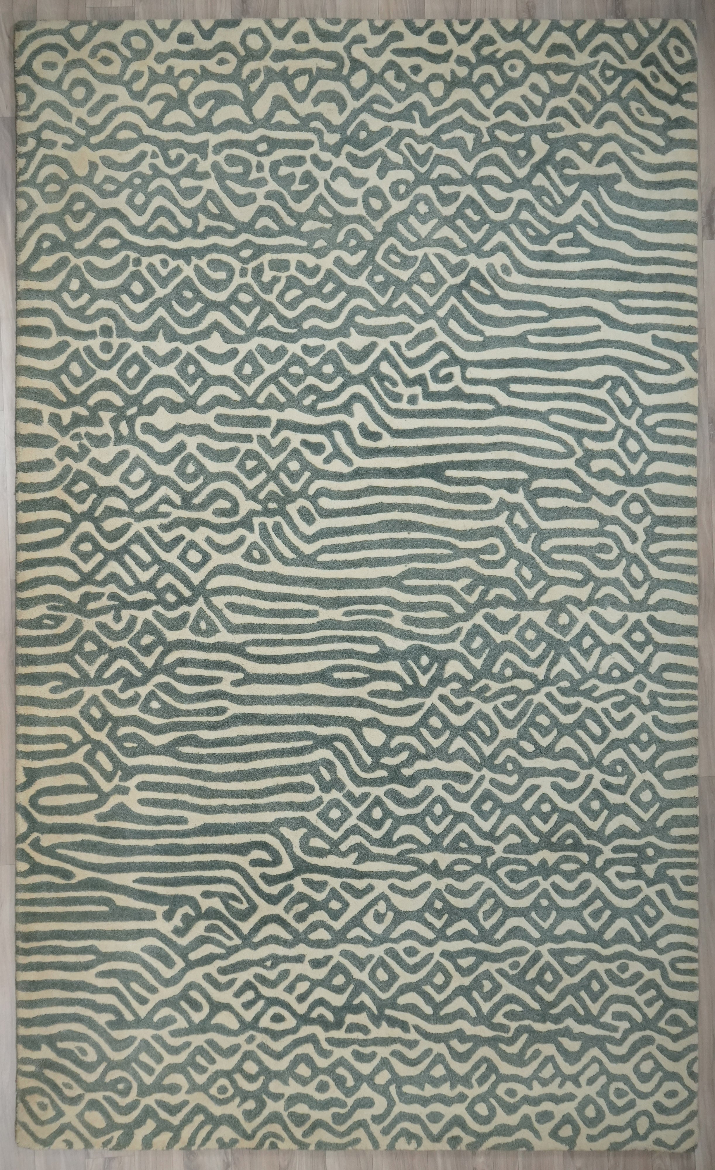 Top view of Glyph hand tufted wool rug showing maze like pattern in sage green.