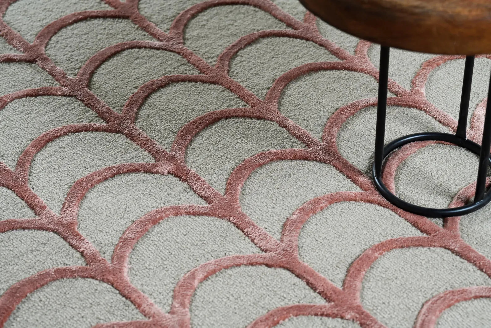 Hand tufted Geometric Scallop hand tufted rug shown in a corner detail view with a wooden stool, highlighting its raised scallop pattern and textured surface.