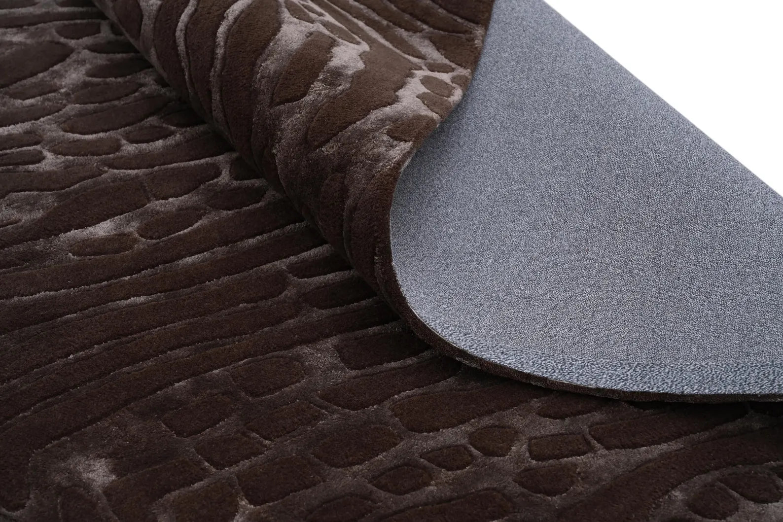 Curved fold of the hand tufted Fossil Ember rug showing texture depth and detailed craftsmanship.