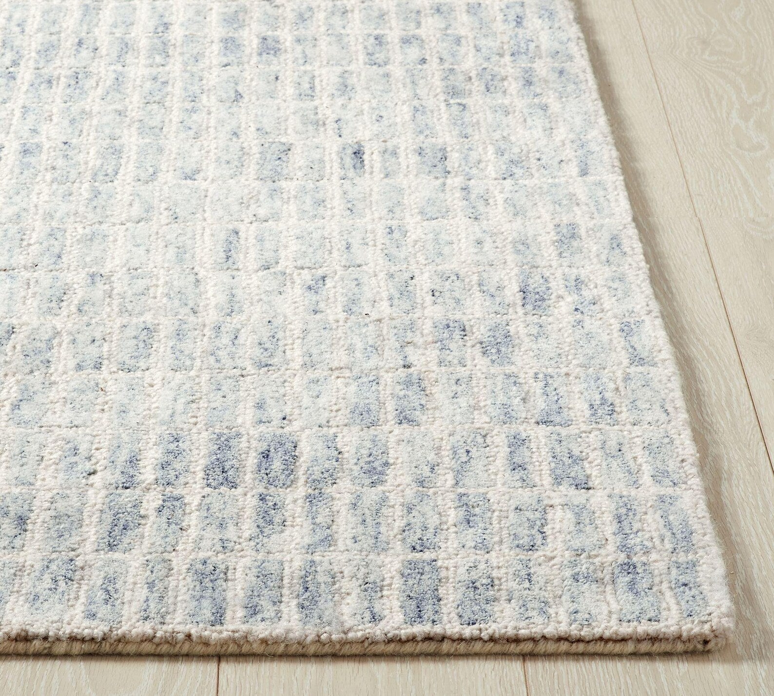 Corner view of Ocean Breeze Rug showing textured grid pattern and soft blue tones