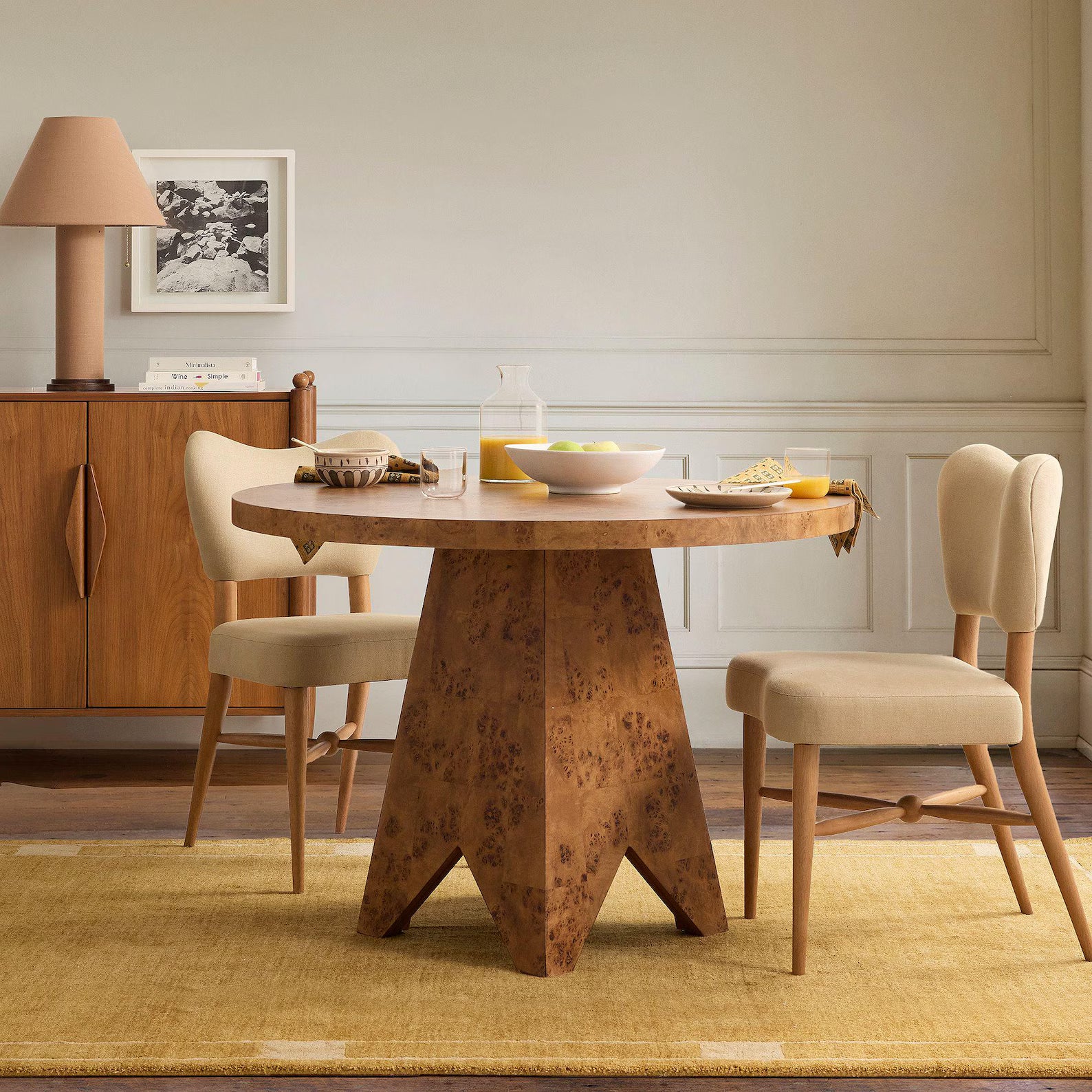 Ochre color mid-century modern hand tufted rug placed under a wooden dining table and beige chairs in a light neutral dining room.