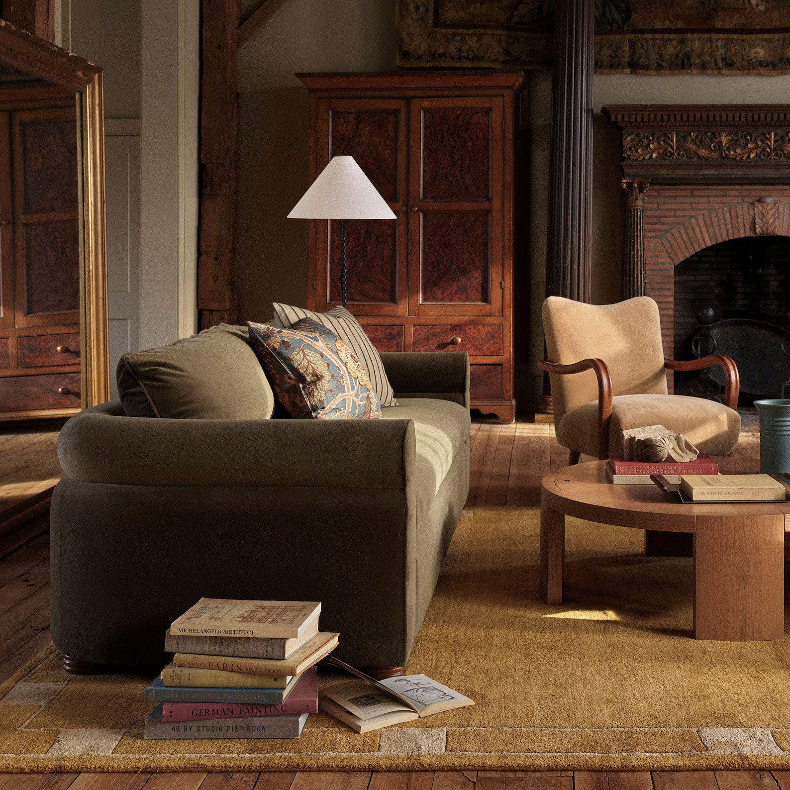 Ochre color mid-century modern hand tufted rug styled in a warm living room with a green sofa, beige armchair, wooden furniture, and earthy interiors.