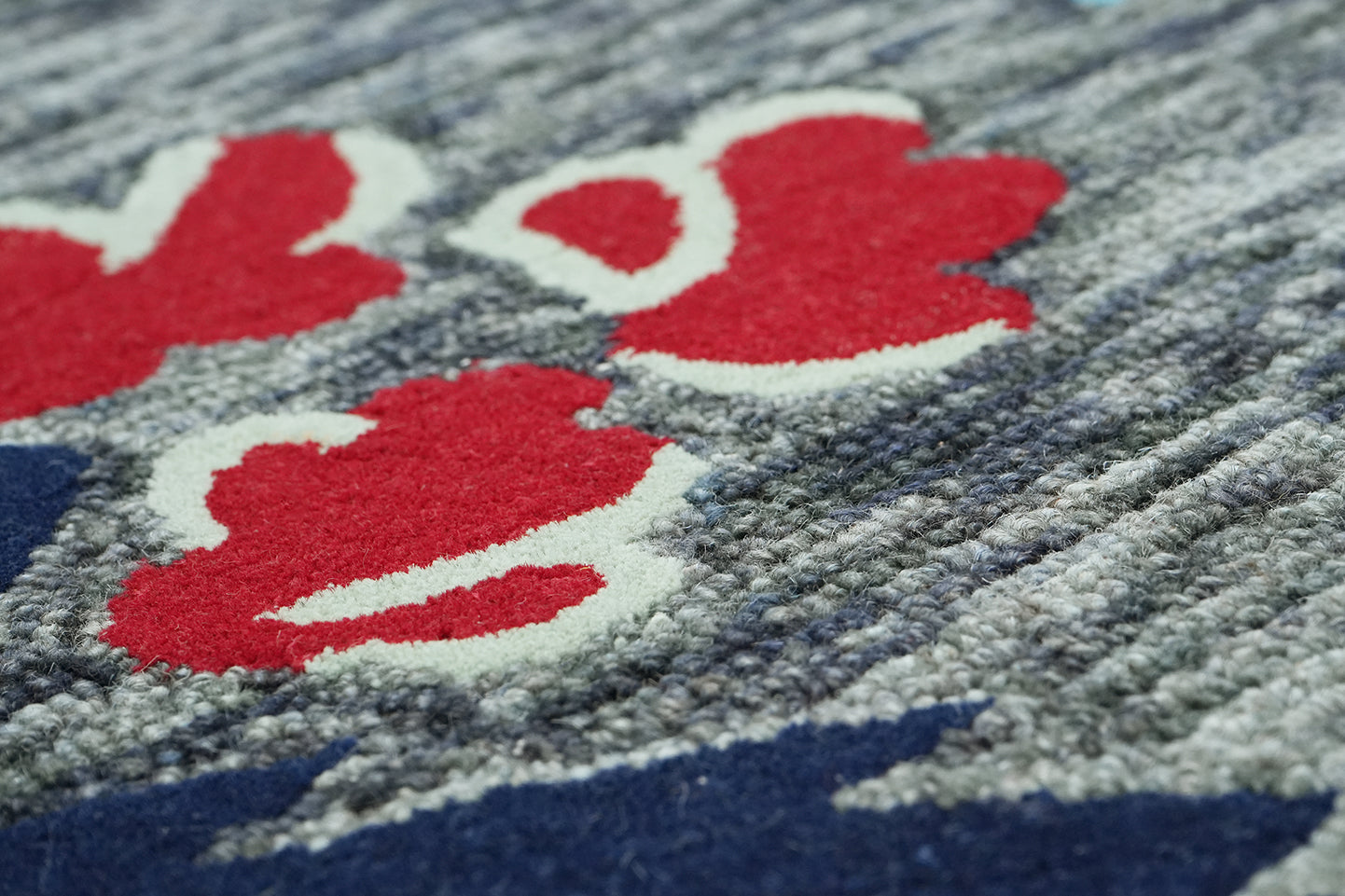 Noctiflora hand tufted wool rug close up pattern showing layered floral elements in warm and cool tones against a grey base