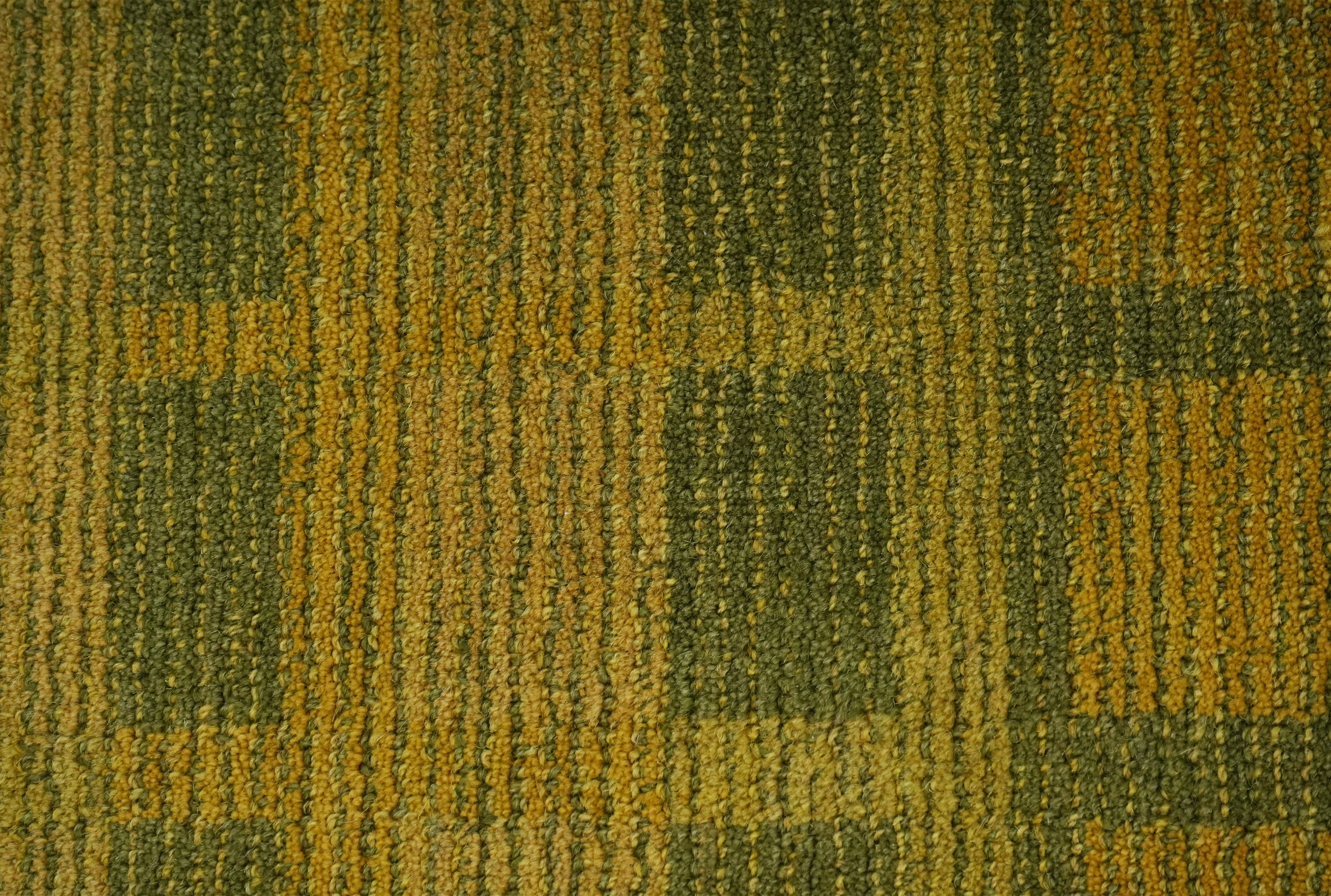 Close up pattern detail of Olivara hand tufted rug in mustard and green tones.