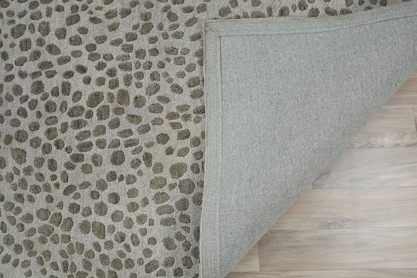 Folded corner view of Pebble Design Wool Rug hand tufted from wool showing the pebble pattern surface and fabric backing
