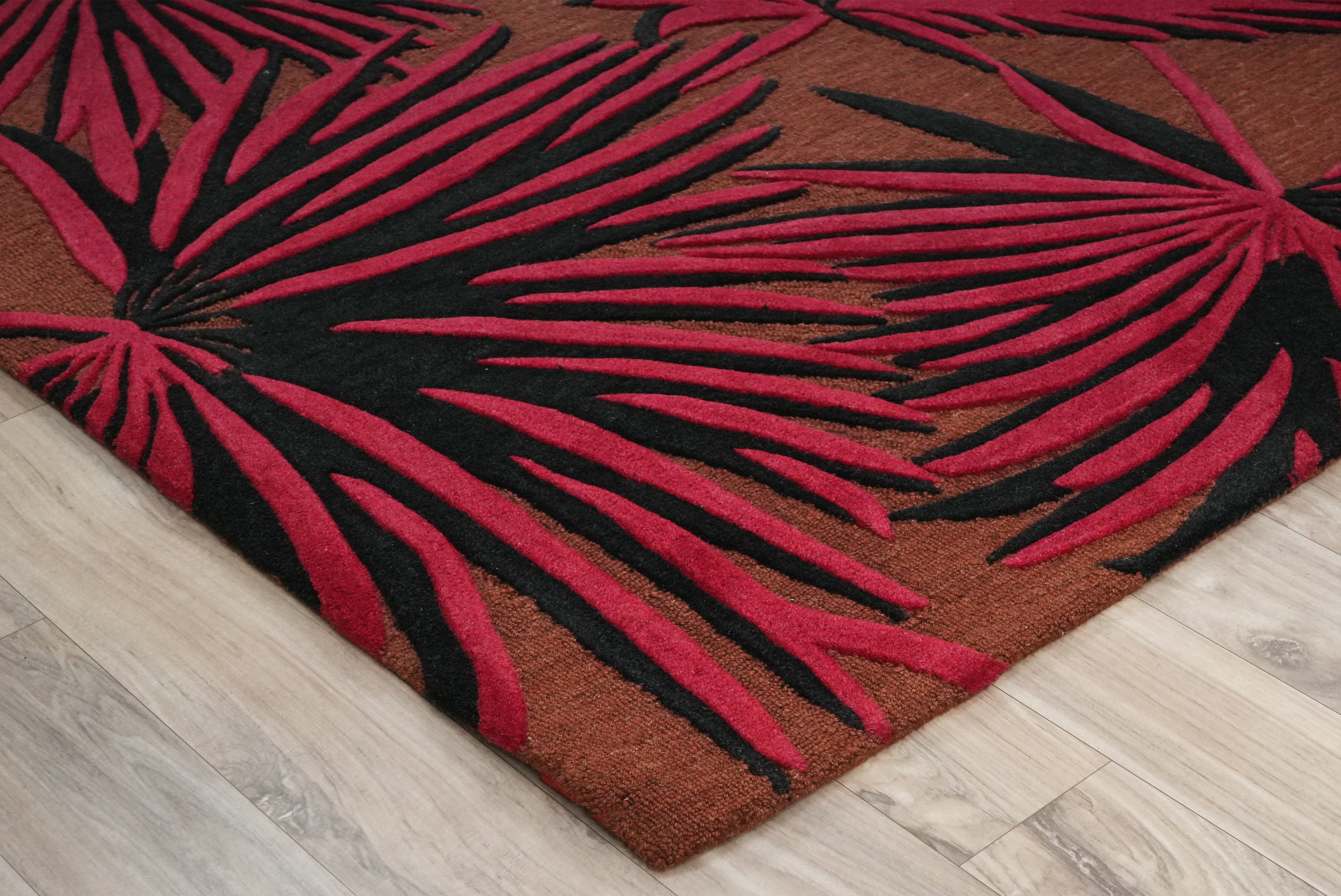 Angled view of Red Palm Noir tropical hand tufted rug with raised palm leaf texture.