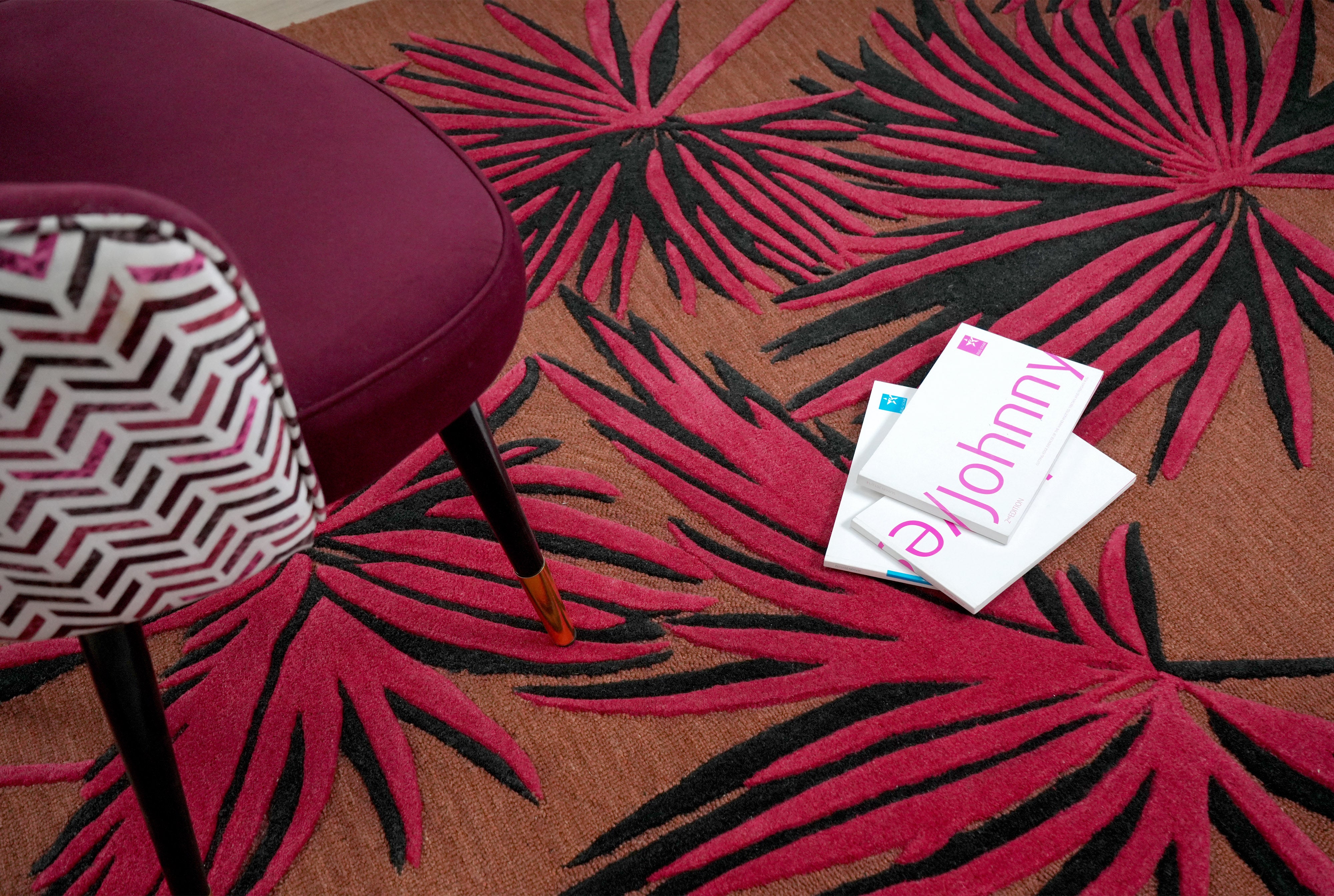 Red Palm Noir hand tufted rug styled in modern living room with bold red and black palm leaf design.
