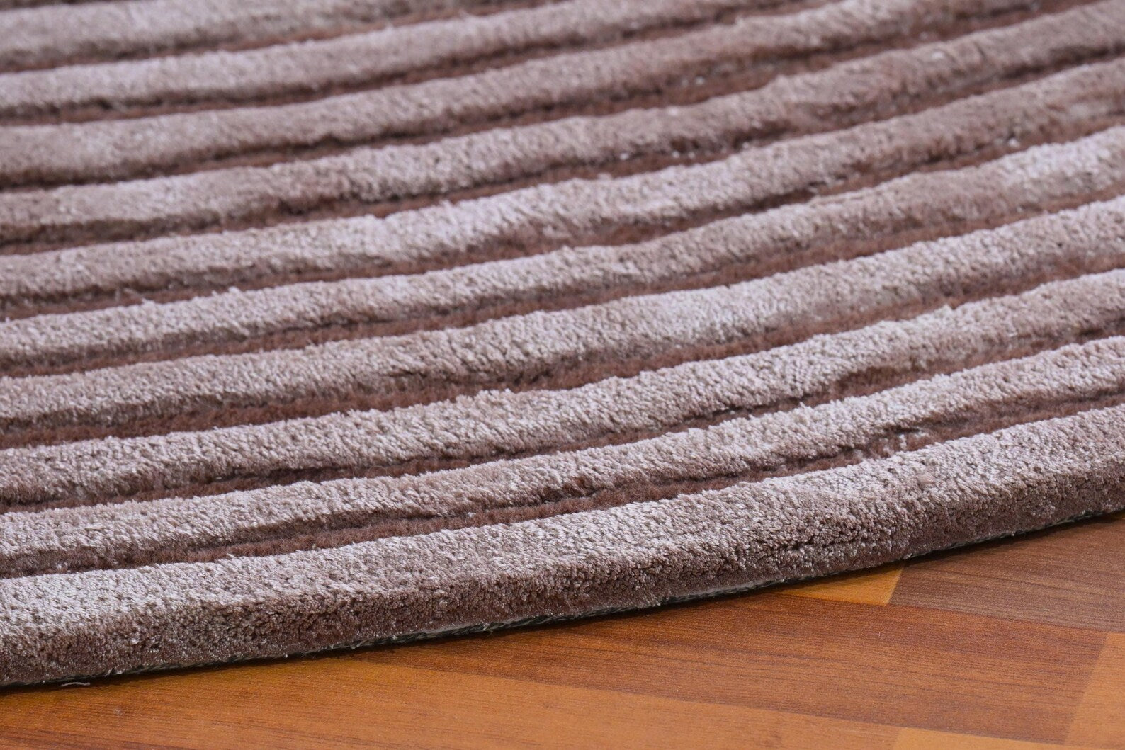Side angle view of Circular Ribbed Rug highlighting raised ribbed texture and unique sculptural cut detail.