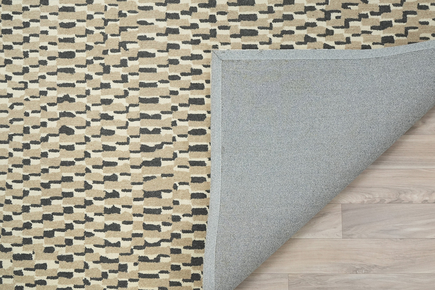 Staggered Dash Wool Rug showing folded corner with hand tufted wool surface and fabric backing detail