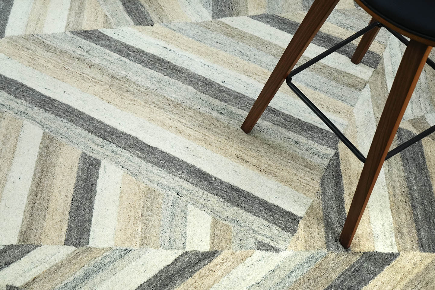 Strata Shift Rug placed in a living space showing layered diagonal stripes in soft beige and grey tones