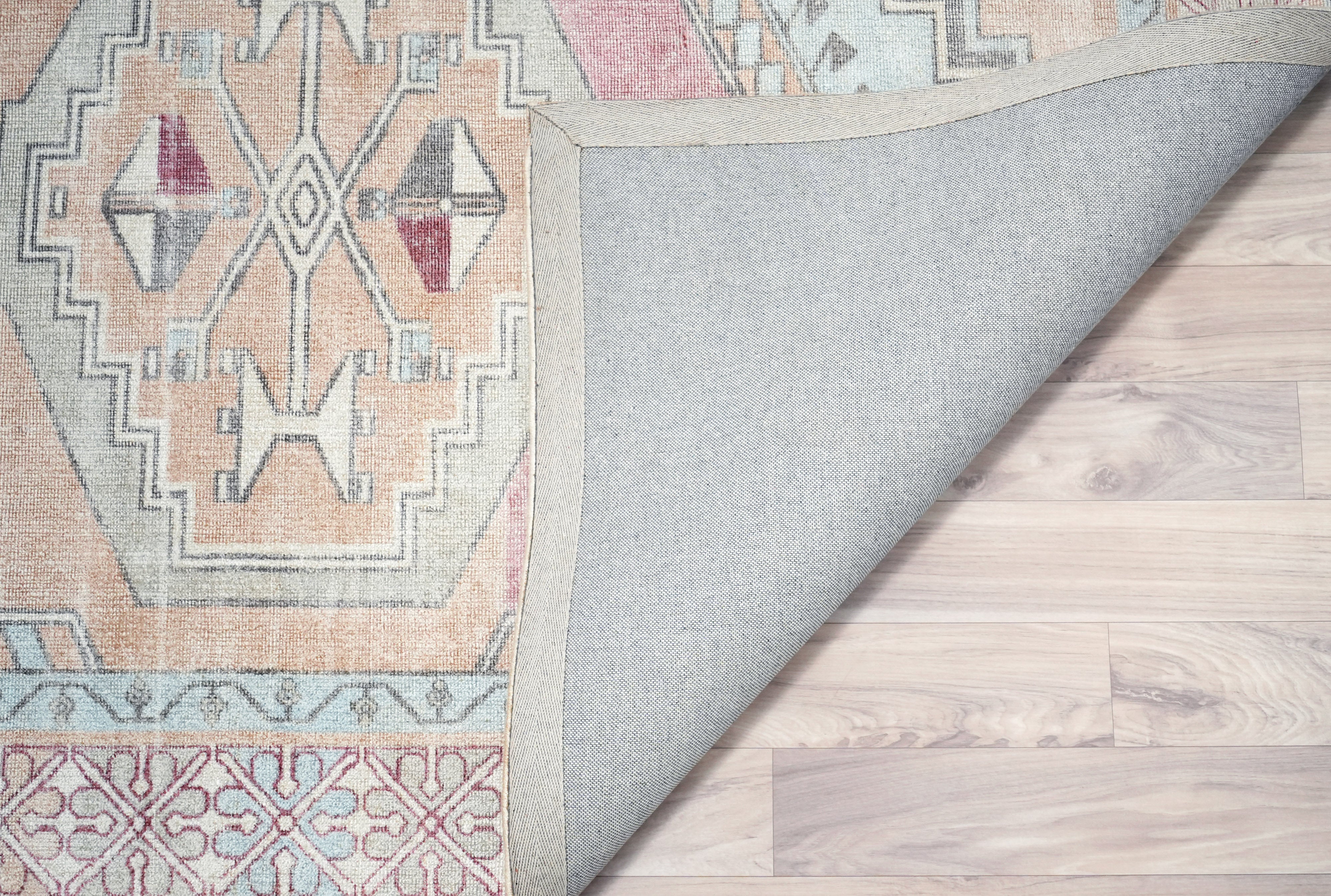 backside view of Willowmere wool hand tufted rug showing cotton backing and vintage medallion pattern in blush soft blue sand beige and ivory tones.