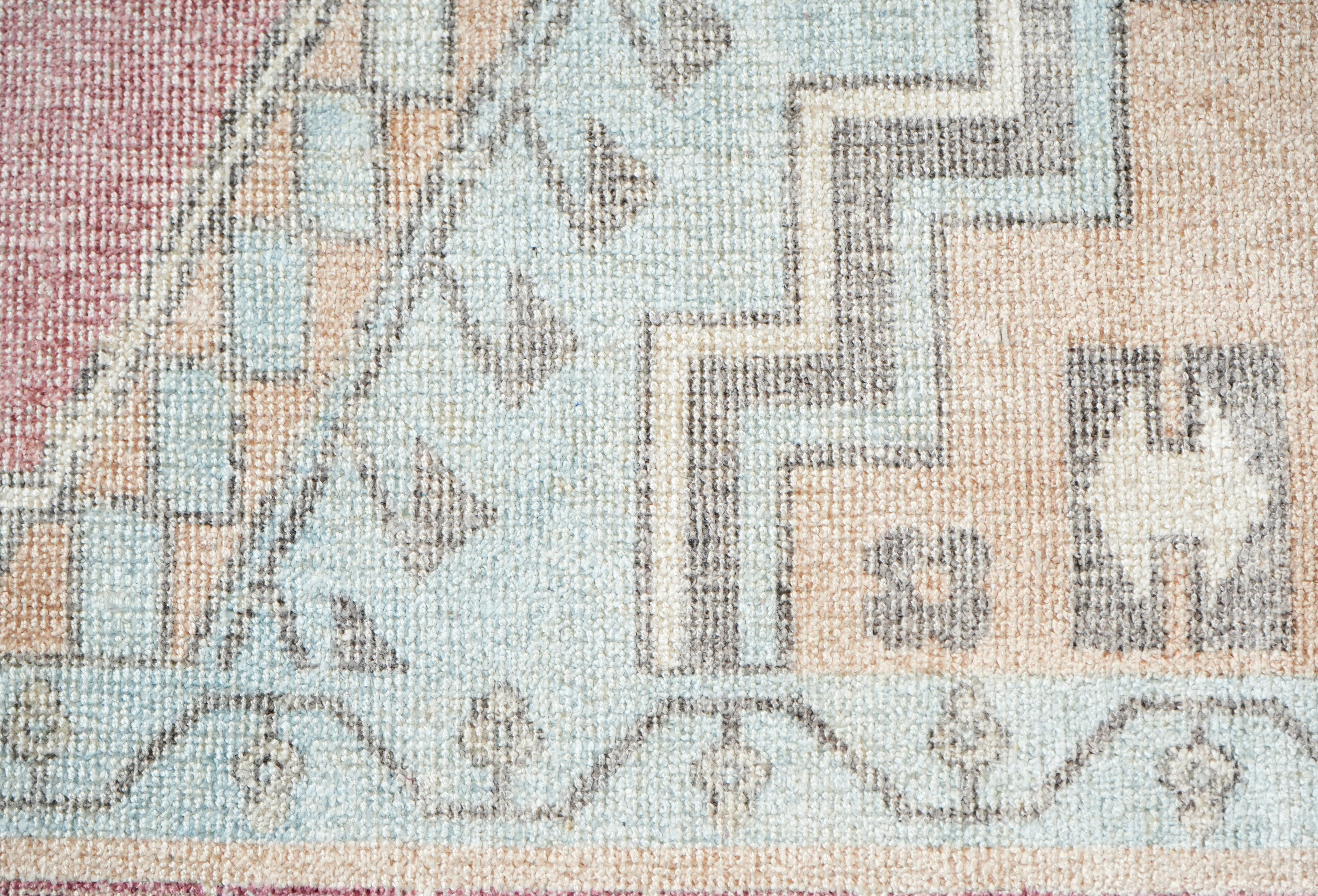 close up of Willowmere wool hand tufted rug showing vintage medallion pattern in blush soft blue sand beige and ivory tones